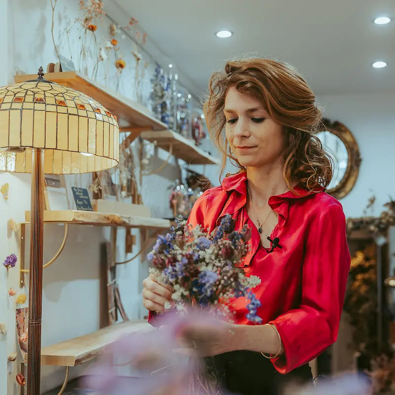 Charlotte réalisant un bouquet pour expliquer la technique de la vrille dans le cadre d'un atelier fleurs séchées à la boutique au 47 rue Froide à Caen