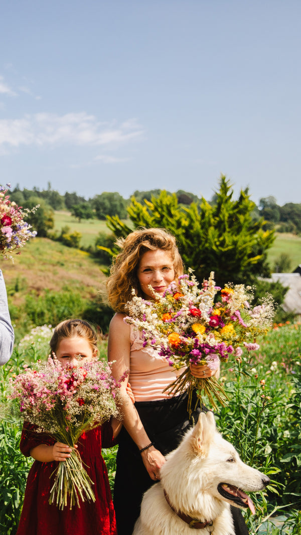 Fleuriste et enfant tenant un bouquet fleur séchée champêtre dans une ferme florale artisanale.