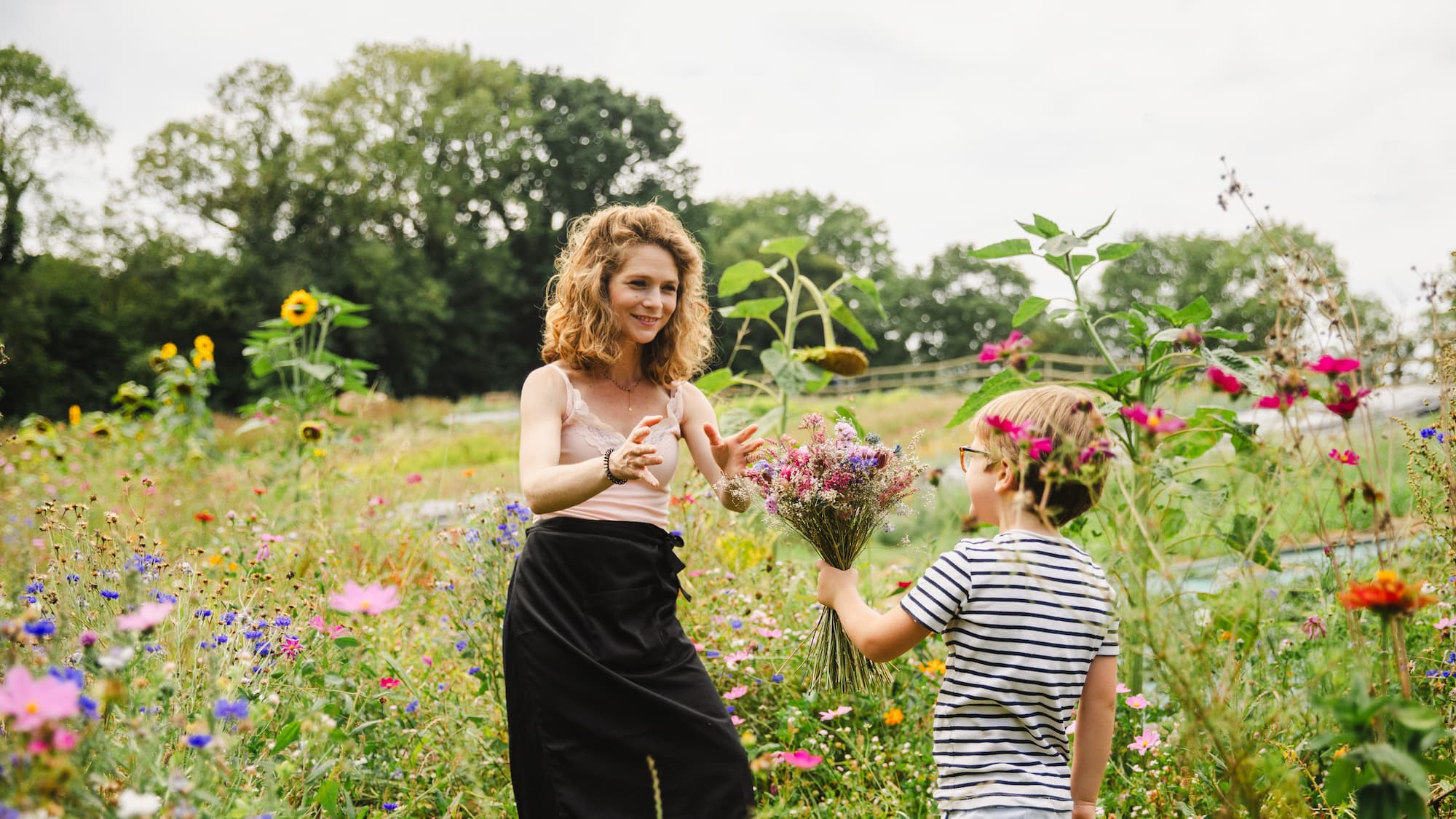 Enfant tenant un bouquet de fleurs séchées champêtre dans une ferme florale artisanale.