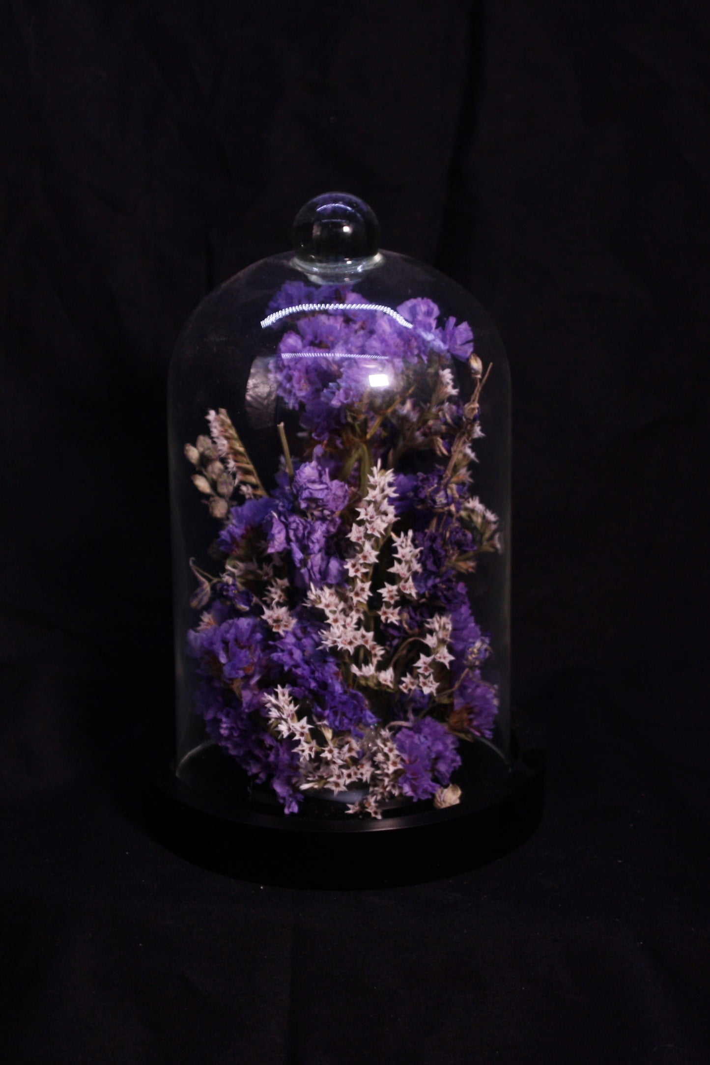 Cloche en verre Fleurs de la Clarté garnie d'une composition florale aux tons bleus.