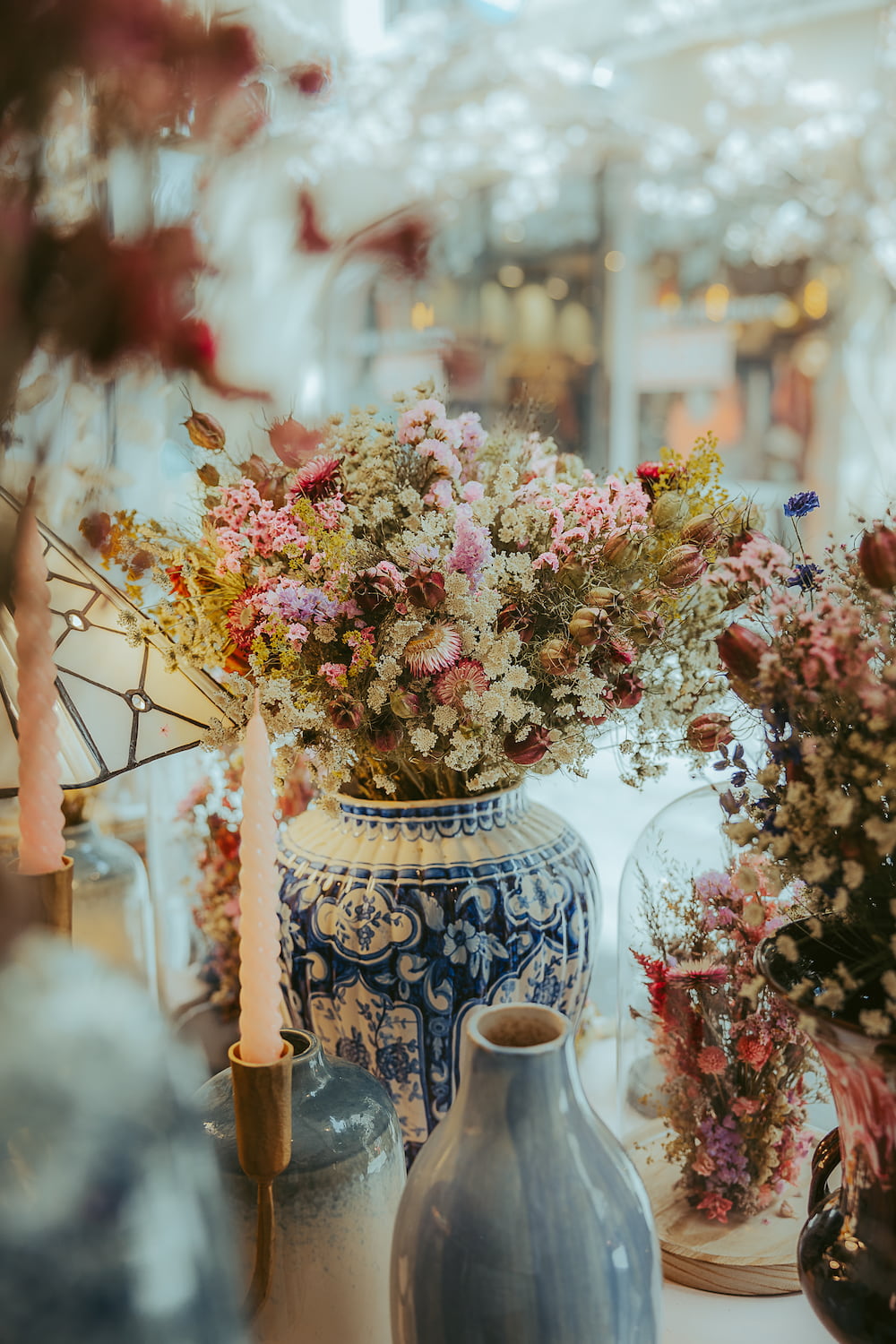 Gros plan sur un bouquet de fleurs séchées aux tons roses et blancs, disposé dans un vase en céramique bleu et blanc, illustrant les bonnes pratiques de conservation à l'abri du soleil direct.