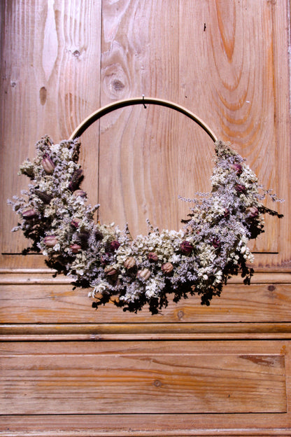 Couronne murale en fleurs séchées naturelles tressée en demi-lune sur un cercle en bois. Création artisanale aux tons blanc