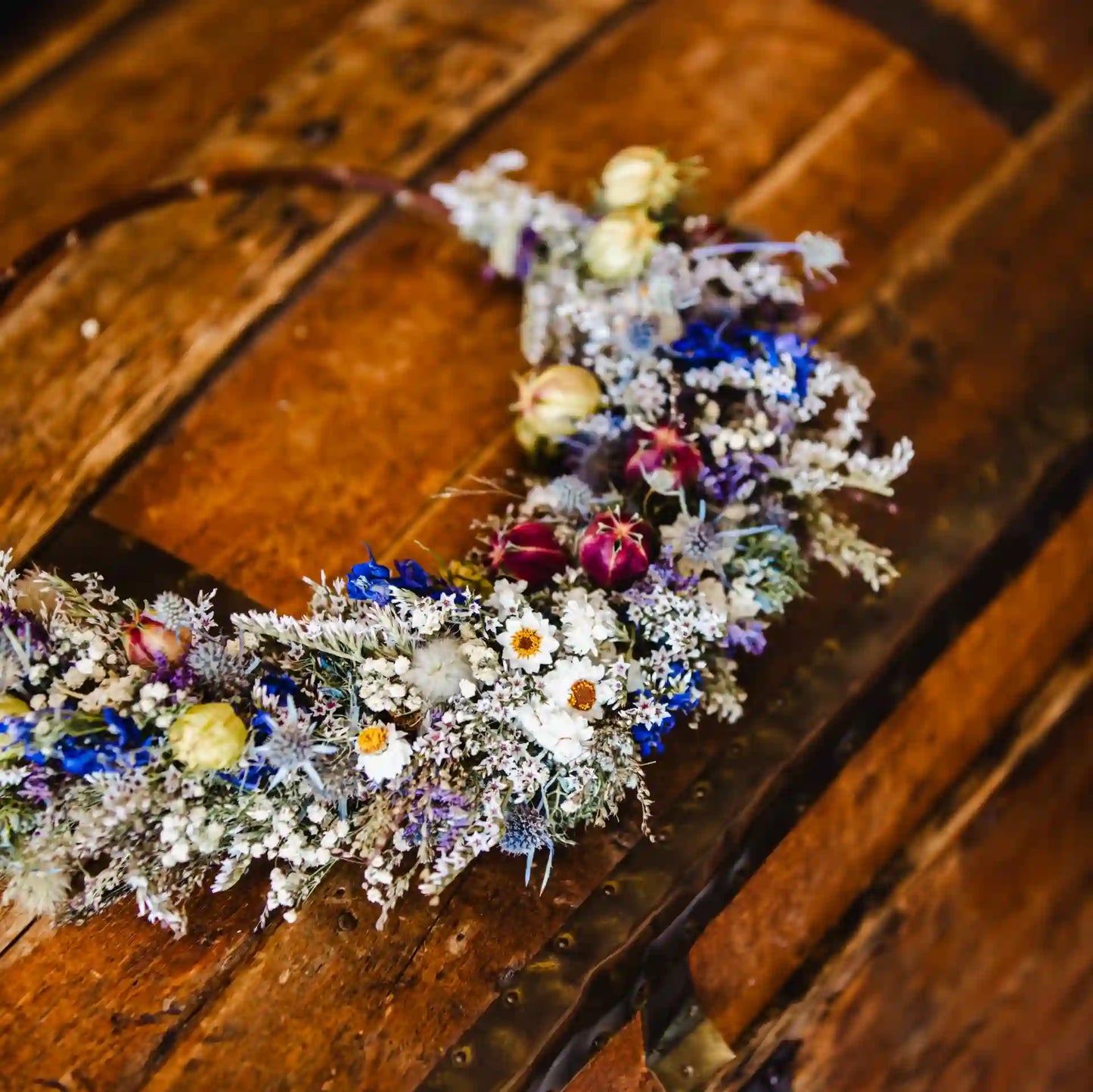 Détail des chardons bleus et delphiniums tressés sur l'anneau métallique de la couronne Cherbourg