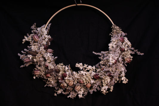 Couronne murale en fleurs séchées naturelles tressée en demi-lune sur un cercle en bois. Création artisanale aux tons blanc