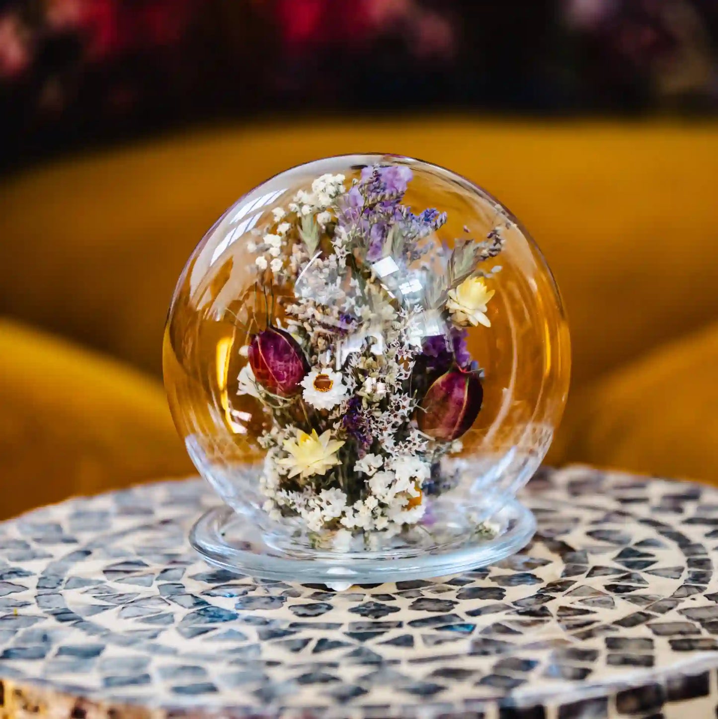 Cloche sphérique en verre transparente protégeant de délicates fleurs séchées claires et parme Étretat