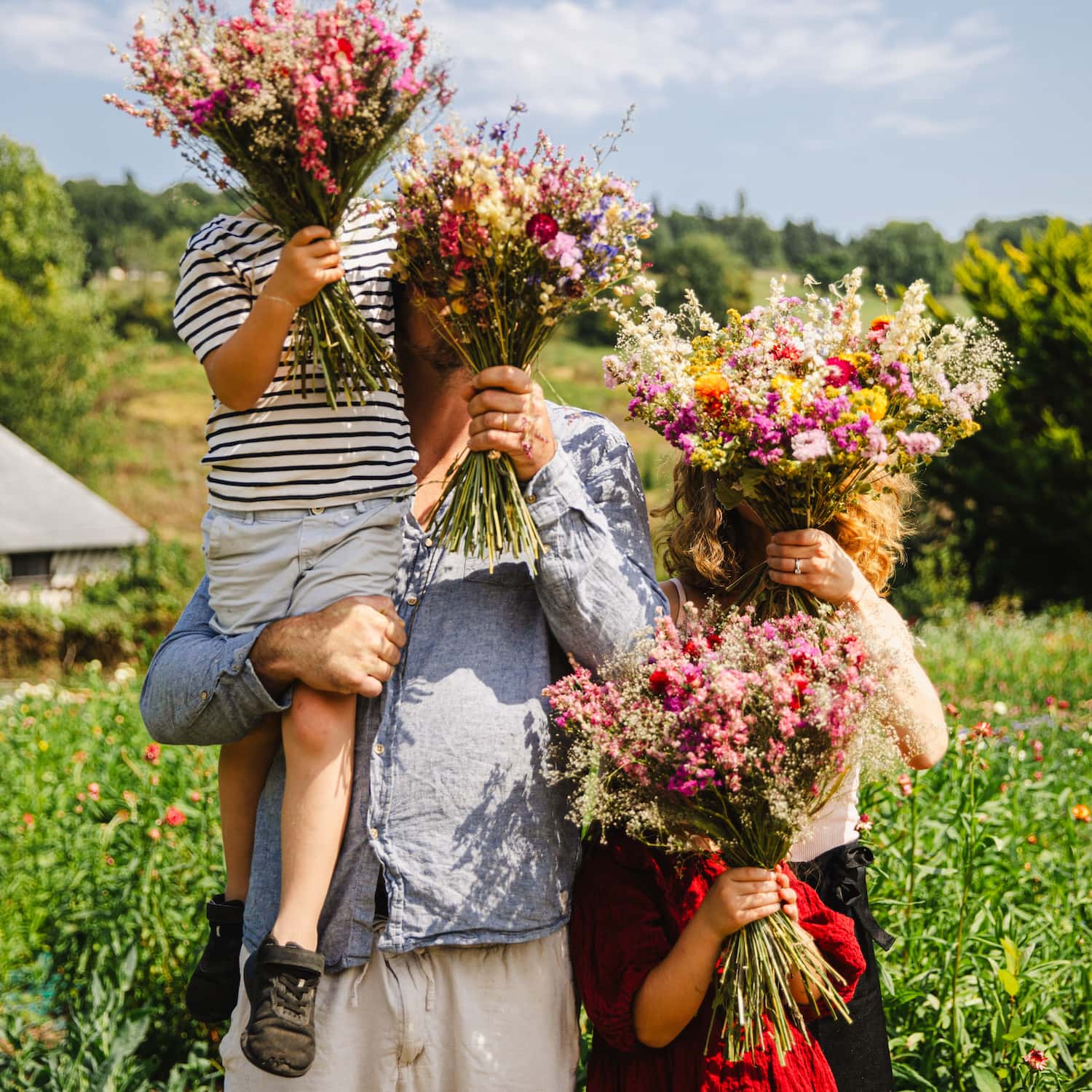 Portrait de famille des fondateurs de la ferme florale Fleurs de la Clarté en Normandie, au milieu de leur production de fleurs françaises.
