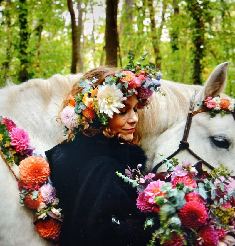 Jeune mariée avec son bouquet de fleurs fraiches et sa couronne de tête avec son cheval, lui aussi fleuri !